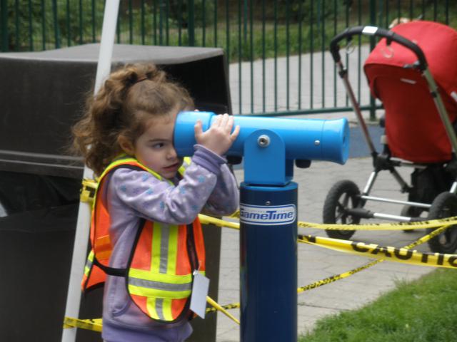 Curious child looking through playground telescope