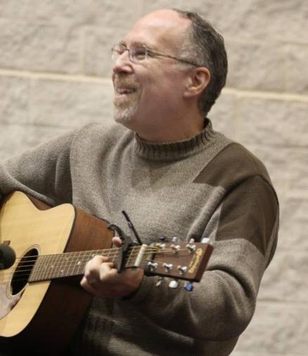 Rabbi Shawn Zevit, smiling man playing guitar