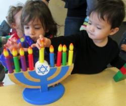 two little kids playing with wooden menorah